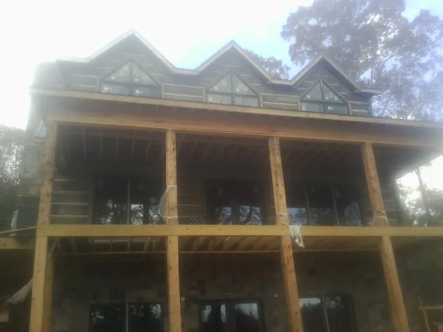Dormers and porch framing on a large log home under construction — Roof Coating work by our crew in Prairieburg
