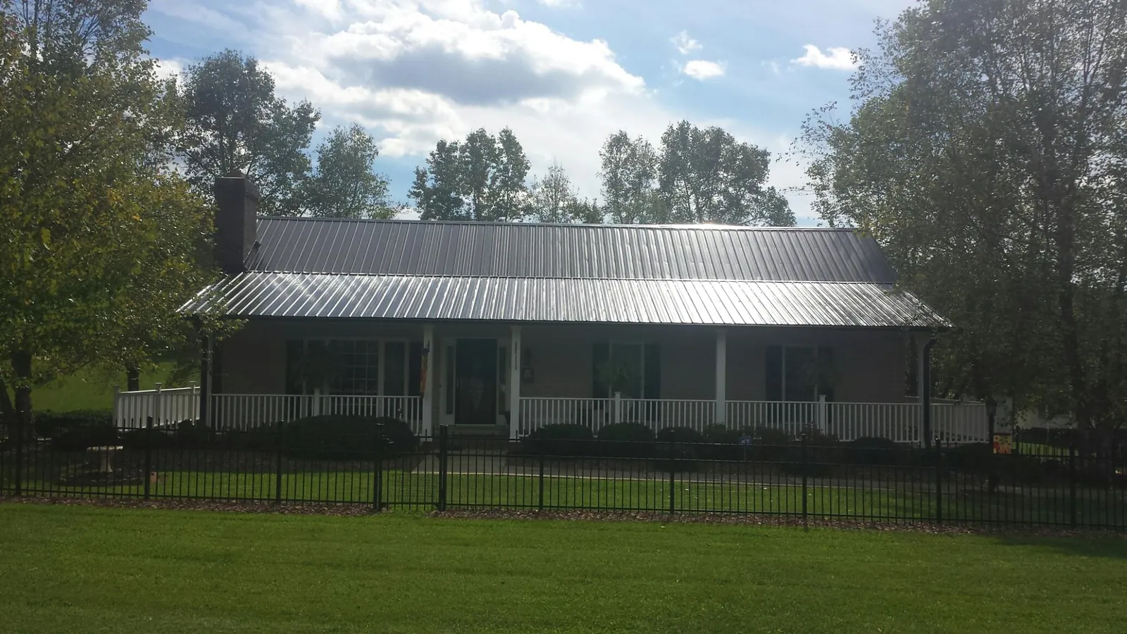Gray metal roof on a brick ranch with a full width front porch — Gutter Guard Installation work by our crew in Prairieburg