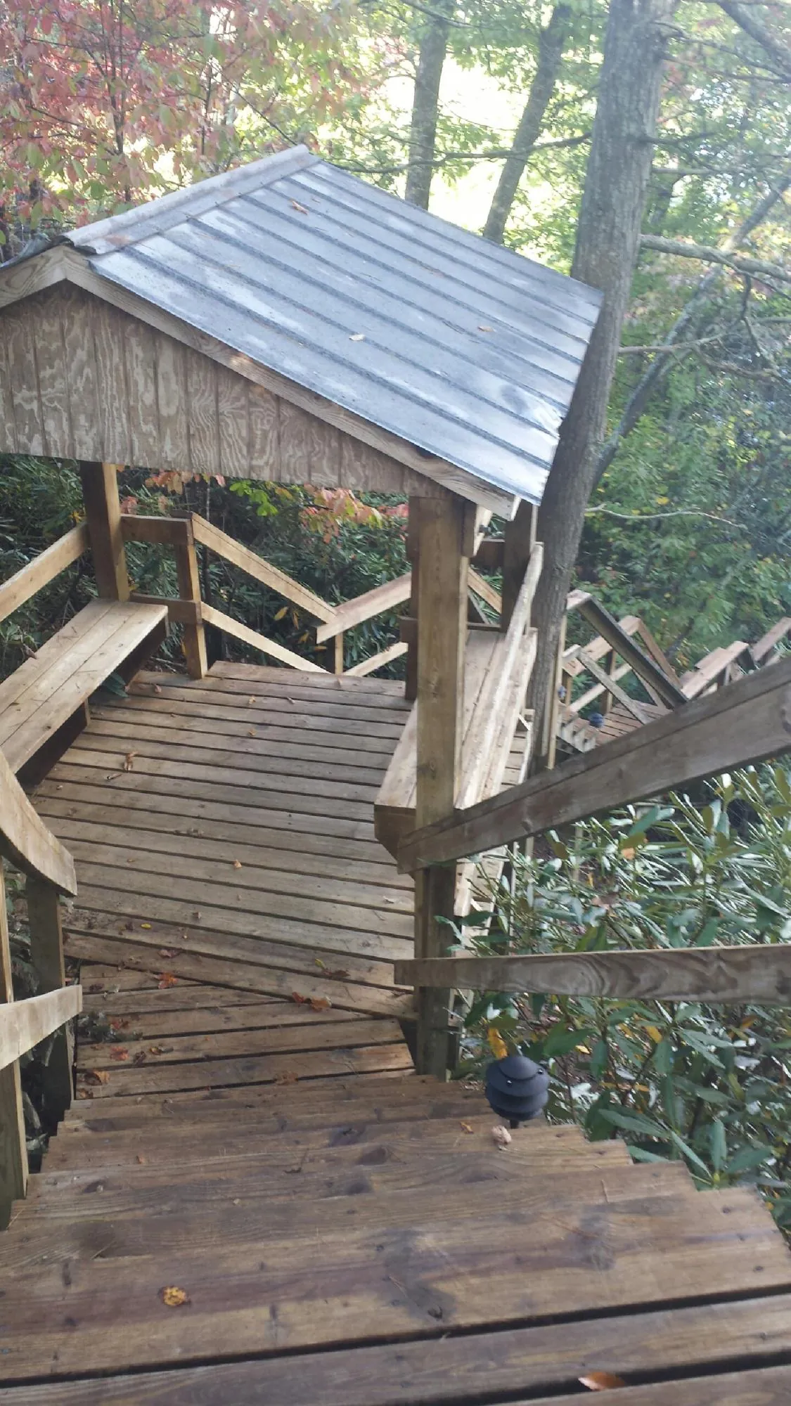 Metal roofed shelter over wooden steps on a wooded walkway — Skylight Repair & Installation work by our crew in Prairieburg