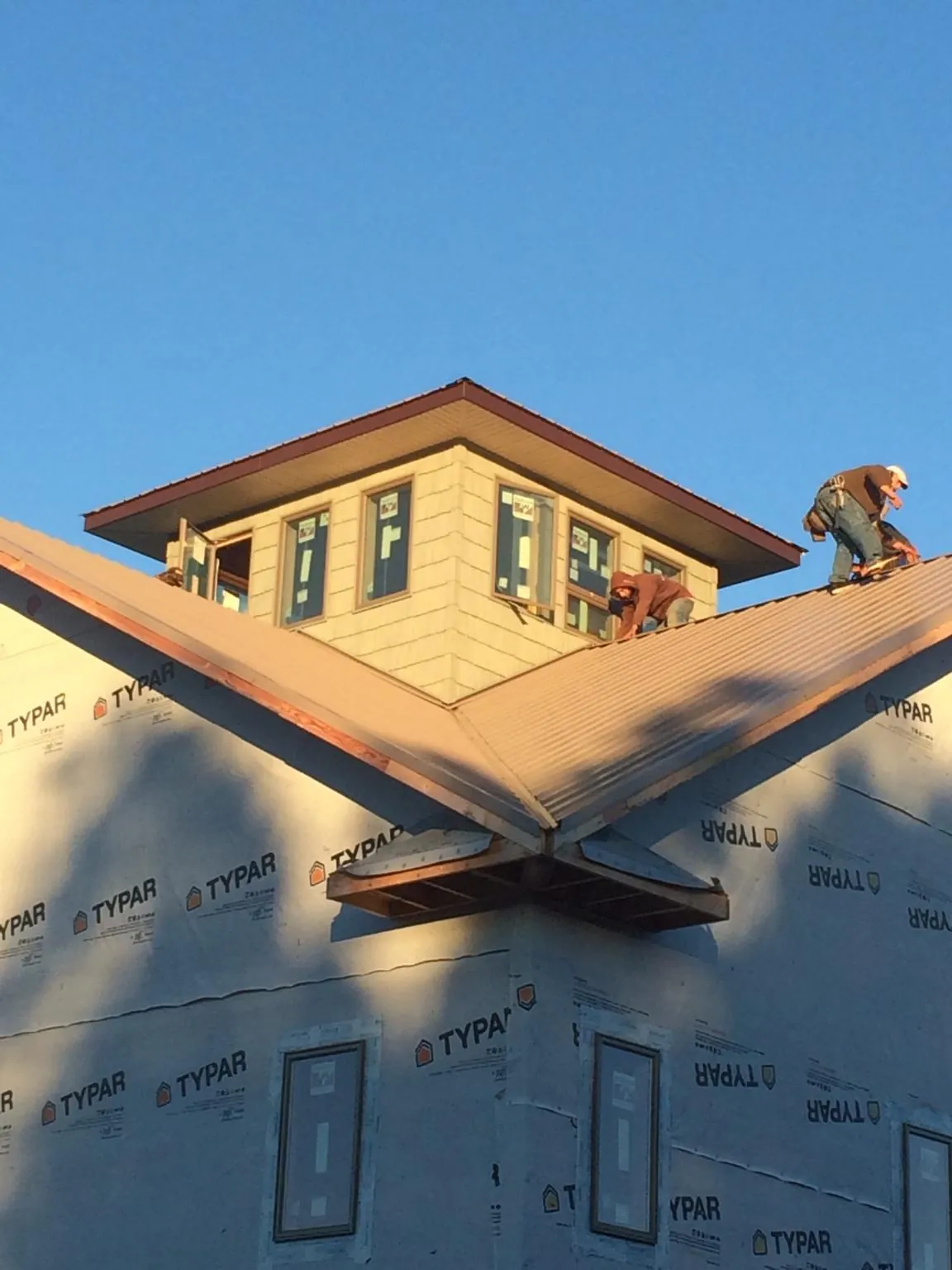Roofers working around a rooftop cupola on a new metal roof at sunset — Roof Waterproofing in Prairieburg by Roofing Brothers
